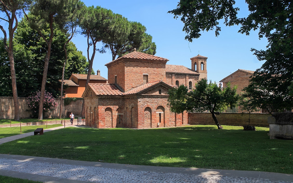 Basilica of San Vitale in Ravenna surrounded by trees, part of UNESCO monuments tour.