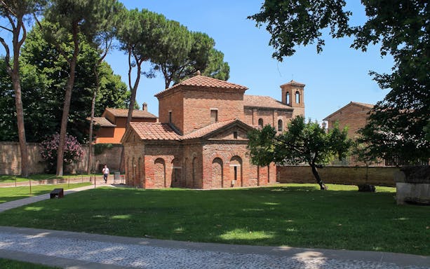 Basilica of San Vitale in Ravenna surrounded by trees, part of UNESCO monuments tour.