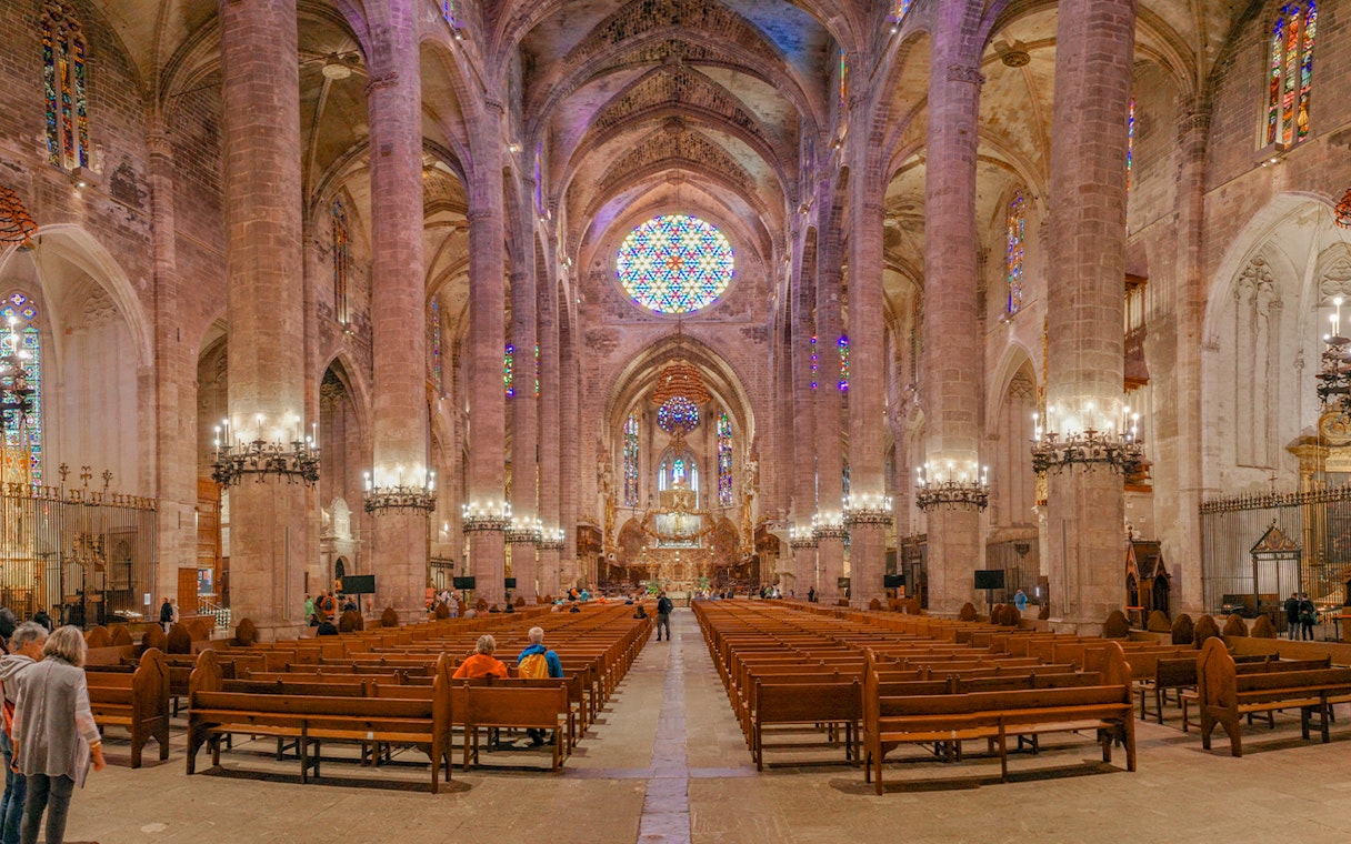 Palma Cathedral interior with stained glass windows and vaulted ceilings.
