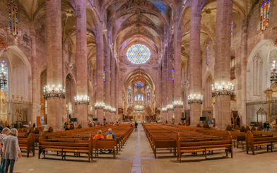 Palma Cathedral interior with stained glass windows and vaulted ceilings.