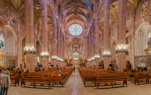 Palma Cathedral interior with stained glass windows and vaulted ceilings.