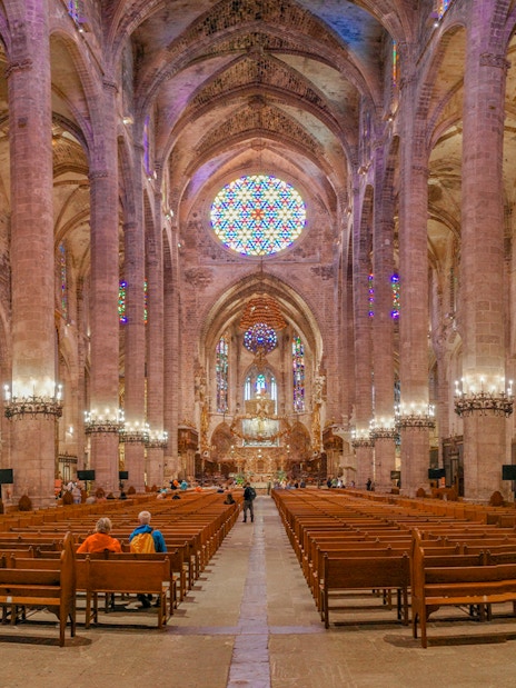 Palma Cathedral interior with stained glass windows and vaulted ceilings.