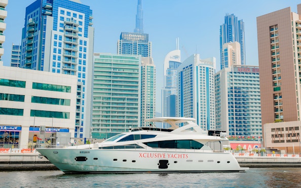 Yacht cruising through canal with Burj Khalifa and Dubai skyline in background.