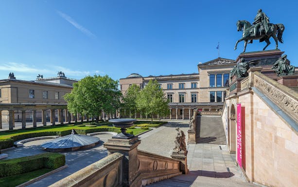 Neues Museum exterior with equestrian statue and landscaped courtyard in Berlin.