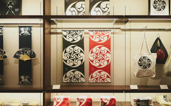 Merchandise display at DRUM TAO Theater Kyoto featuring fans, banners, and tote bags.