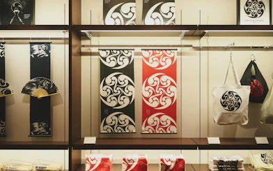 Merchandise display at DRUM TAO Theater Kyoto featuring fans, banners, and tote bags.