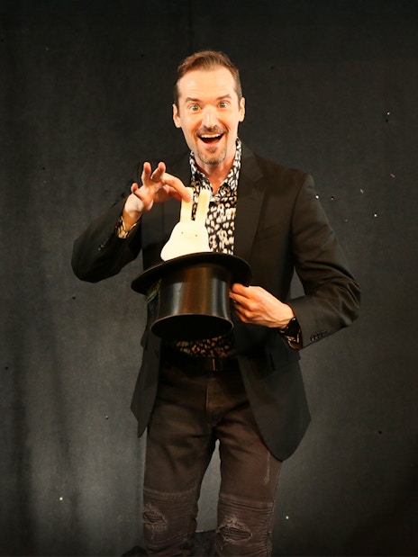 Magician pulling a rabbit from a hat during a show.