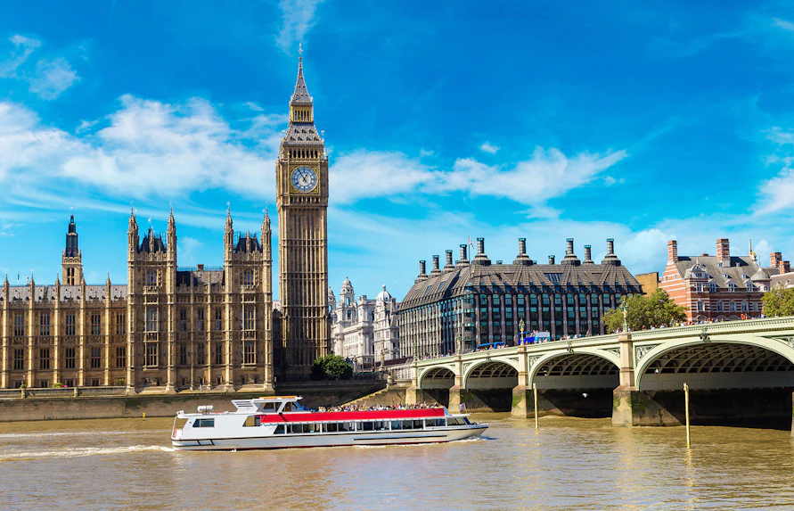 Cruise boat on Thames River near Big Ben and Westminster Bridge, London.