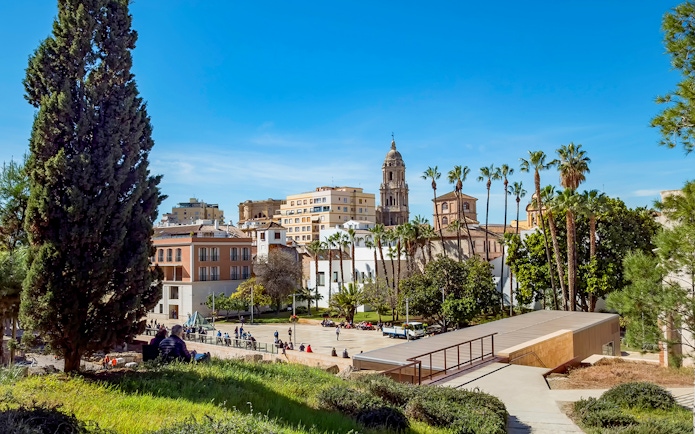 Picasso Museum in Malaga with cityscape and palm trees in the background.