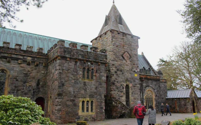 Stone church in Oban with visitors walking nearby.