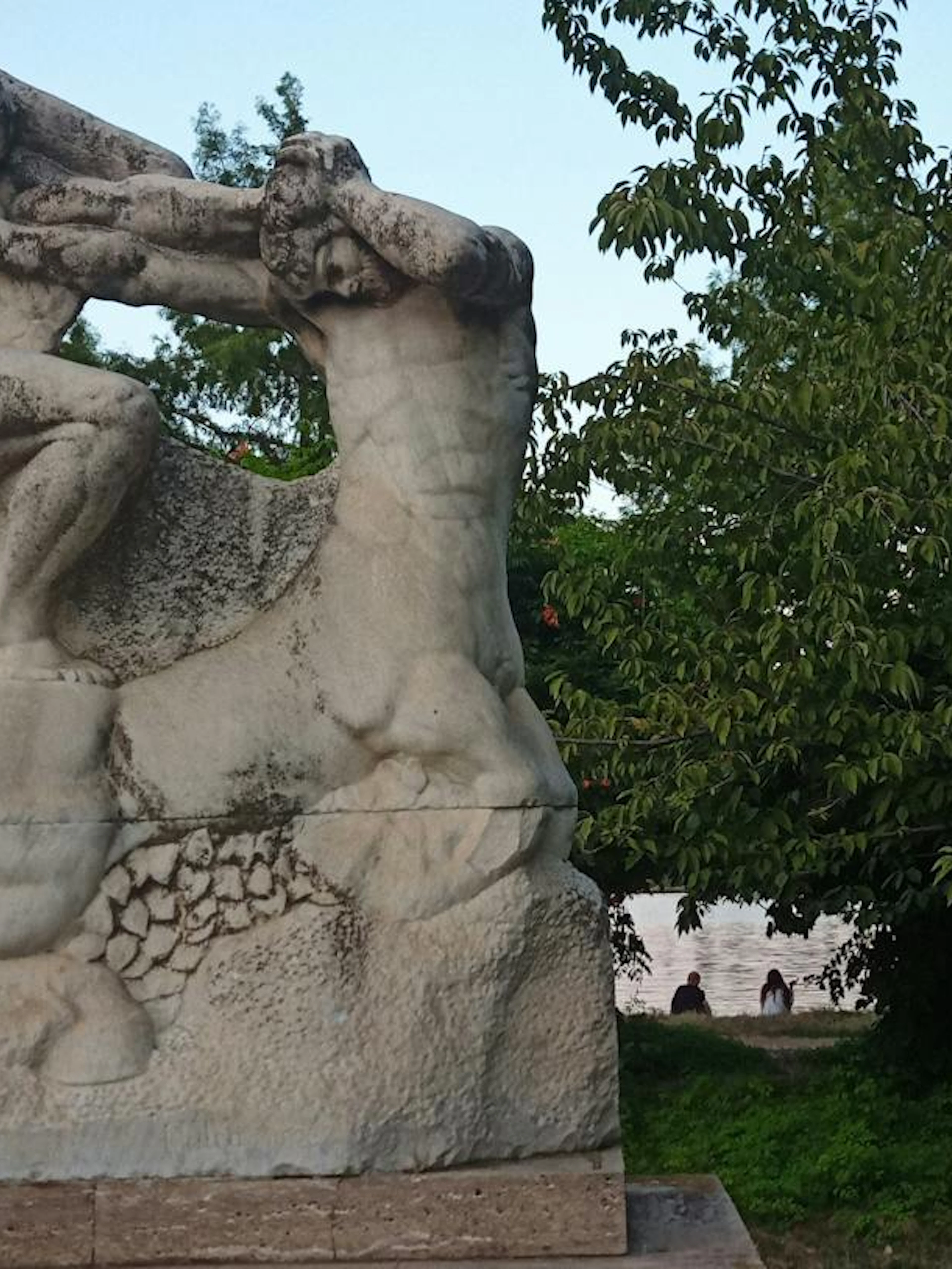Stone sculpture in a park setting, part of the Romantic Bucharest self-guided city exploration game.