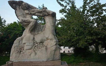 Stone sculpture in a park setting, part of the Romantic Bucharest self-guided city exploration game.