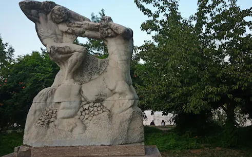 Stone sculpture in a park setting, part of the Romantic Bucharest self-guided city exploration game.