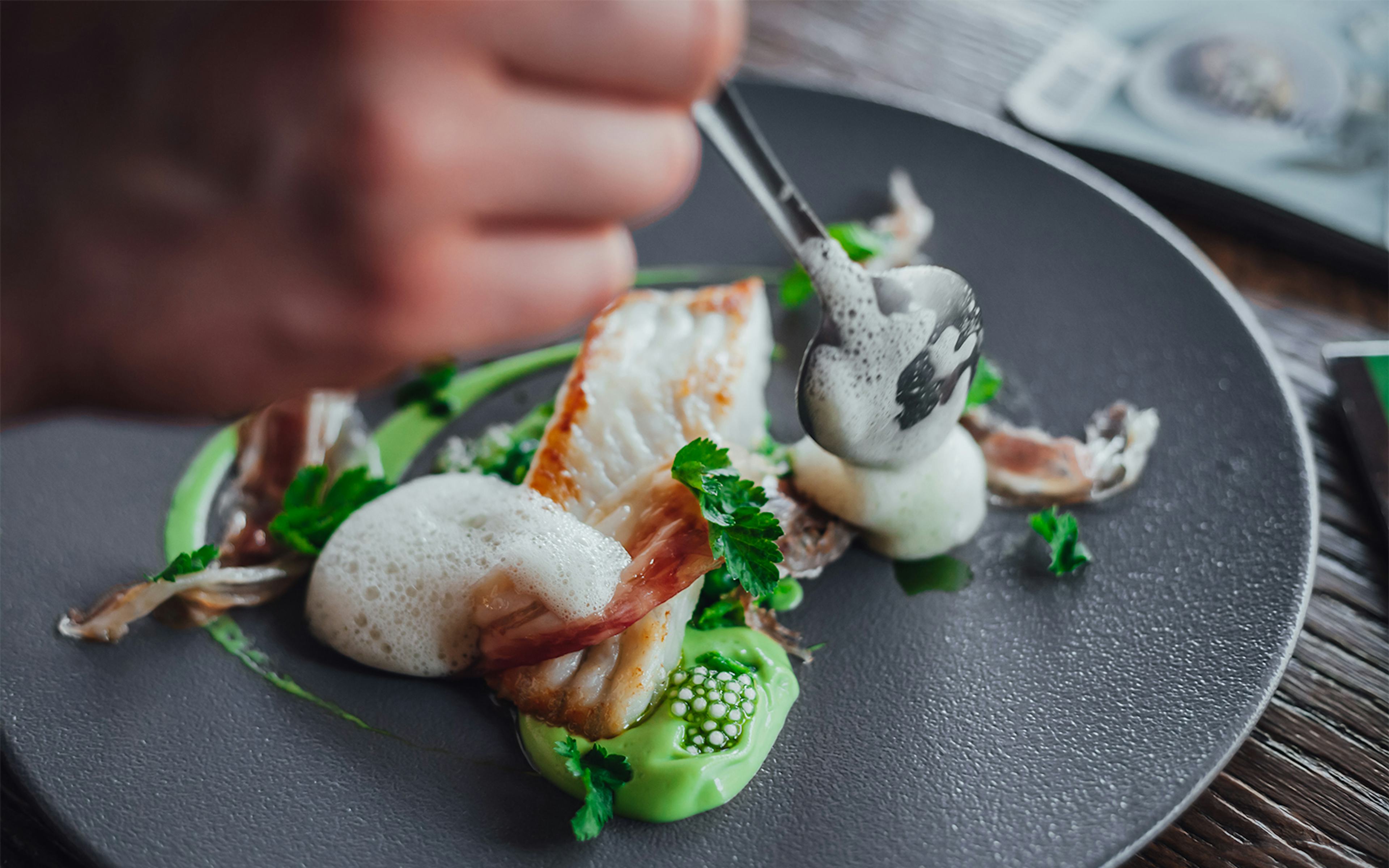 Fine dining dish with foam and greens at a Michelin star restaurant.