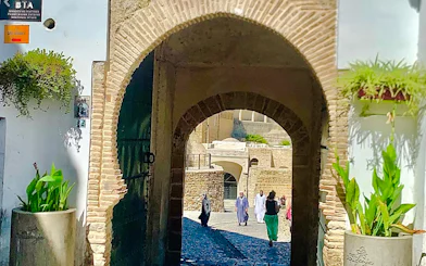 Archway entrance to Tangier Medina with people walking, showcasing local architecture.