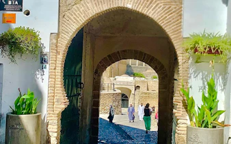 Archway entrance to Tangier Medina with people walking, showcasing local architecture.