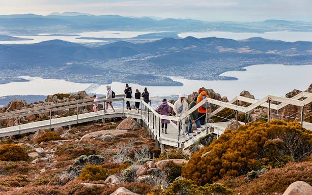 Visitors walking on Mt Wellington boardwalk with views of Hobart, Tasmania in the background.