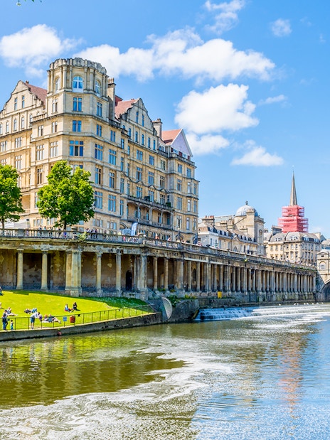 Pulteney Bridge over River Avon in Bath, England, with historic architecture and lush greenery.