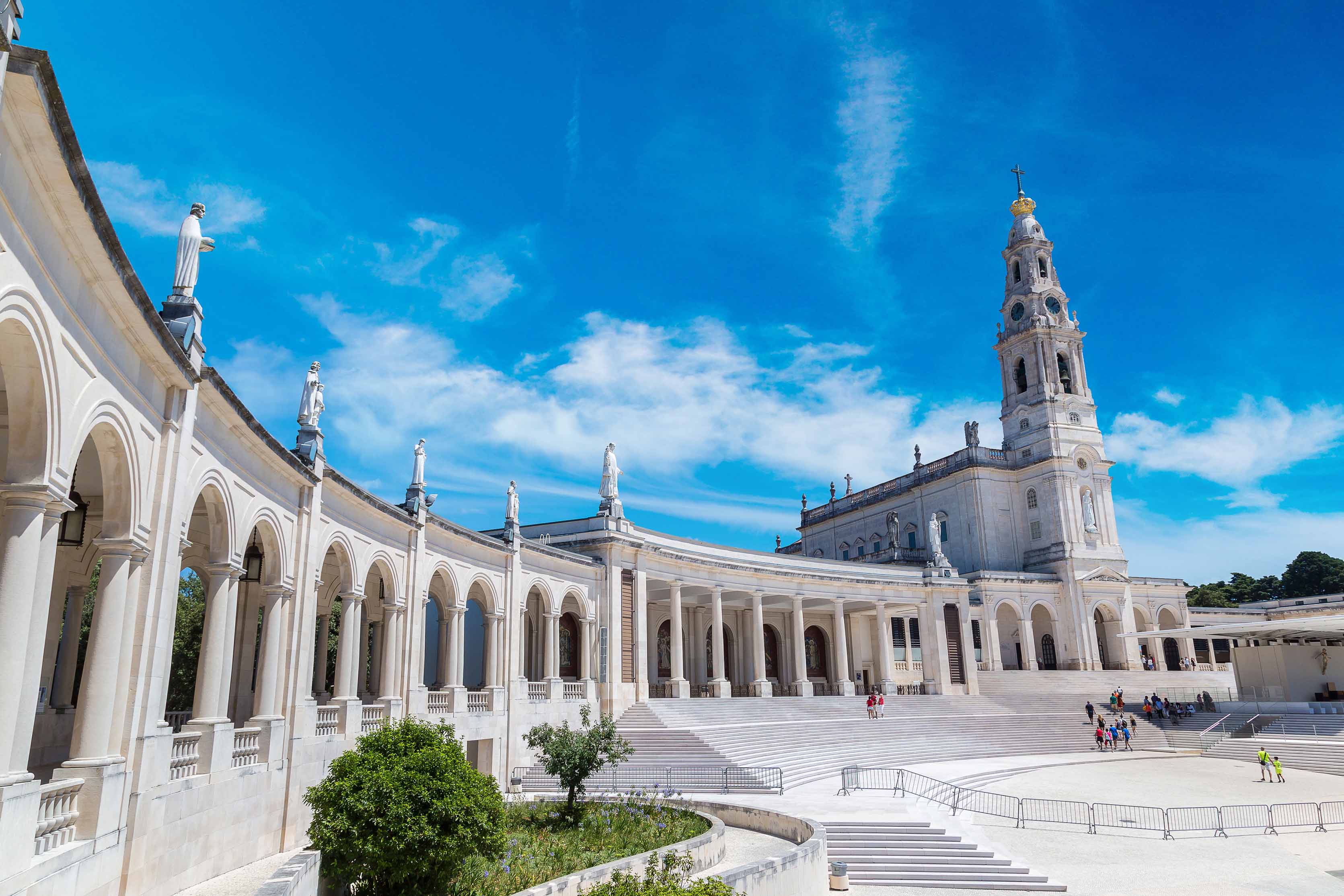 Sanctuary of Fatima with colonnade and basilica under blue sky.