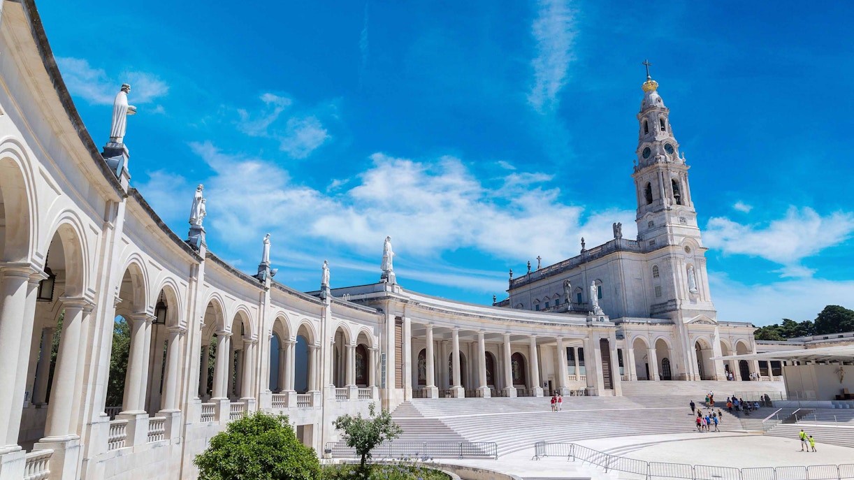 Sanctuary of Fatima with colonnade and basilica under blue sky.