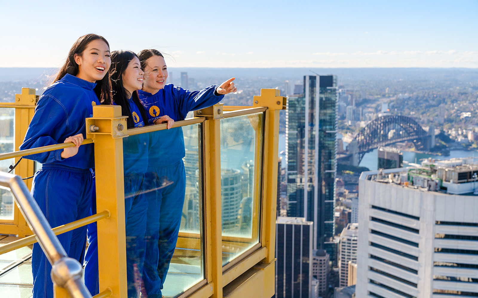 Visitors on Sydney Tower Eye Skywalk overlooking cityscape and Sydney Harbour Bridge.