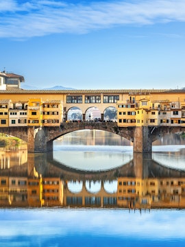 Ponte Vecchio bridge over Arno River in Florence, Italy, reflecting in the water.