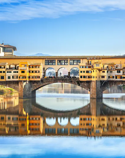 Ponte Vecchio bridge over Arno River in Florence, Italy, reflecting in the water.