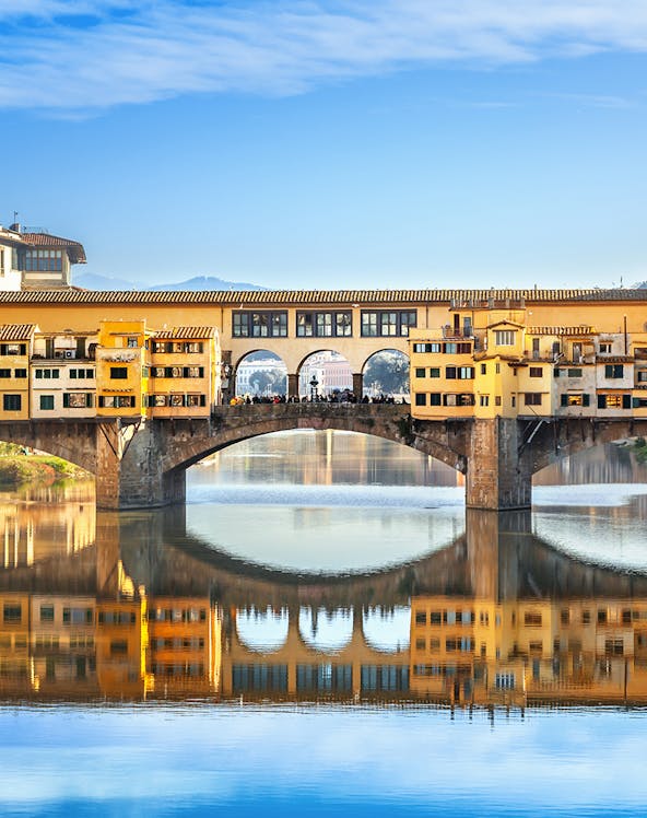 Ponte Vecchio bridge over Arno River in Florence, Italy, reflecting in the water.