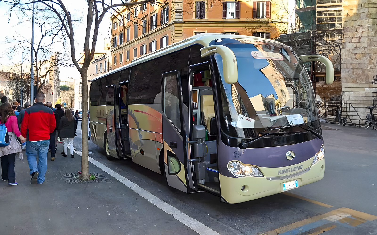 Tourists boarding an AC coach vehicle on a city street.
