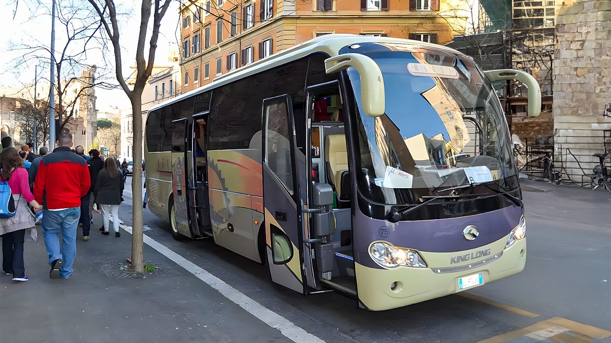 Tourists boarding an AC coach vehicle on a city street.