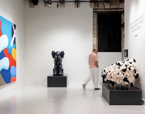 Visitantes vendo as obras de arte de Kaws no Moco Museum Barcelona, disponíveis com ingressos de entrada