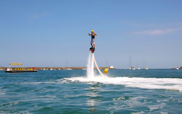 Flyboarder soaring above water in Hurghada with boats in the background.