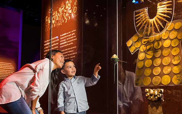 Visitors admire Andean gold artifacts and cultural displays in a museum exhibit.