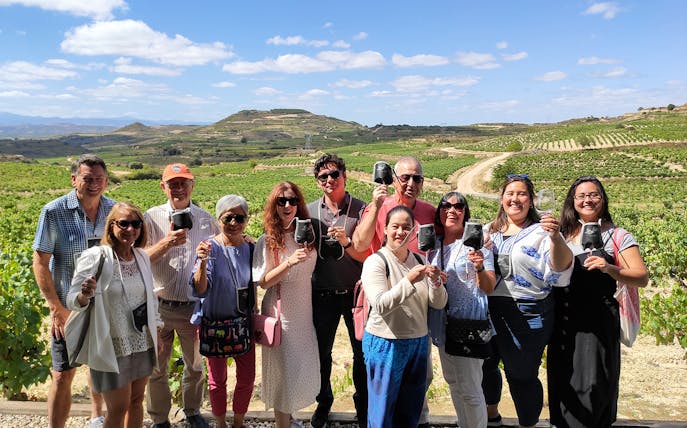 Group enjoying wine tasting at a Rioja vineyard during a tour from Bilbao.