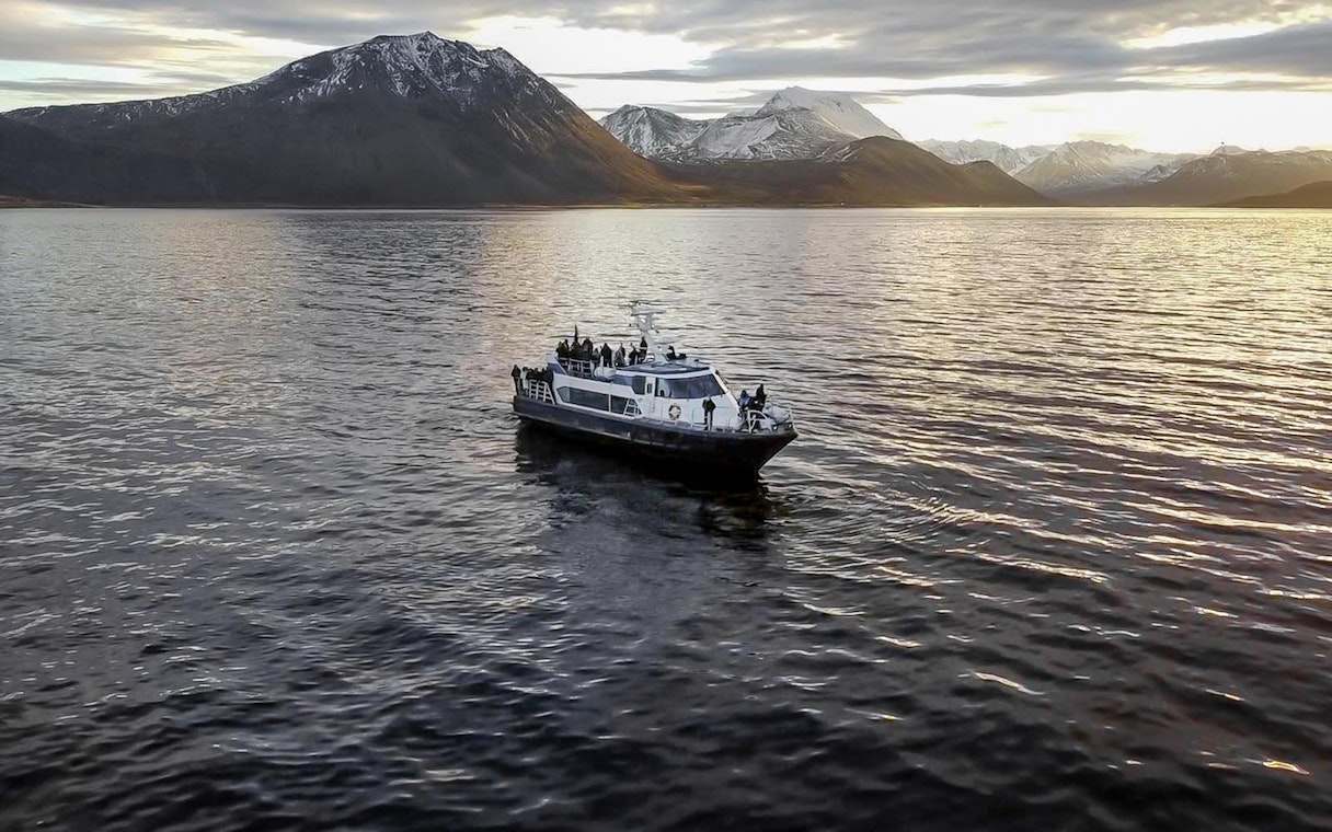 Cruise ship on a whale watching tour with mountains in the background.