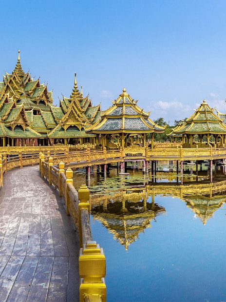 Ancient City Temple with ornate golden roofs over water, Bangkok, Thailand.