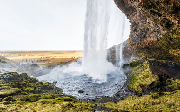 Seljalandsfoss waterfall cascading over mossy cliffs in Southern Iceland.