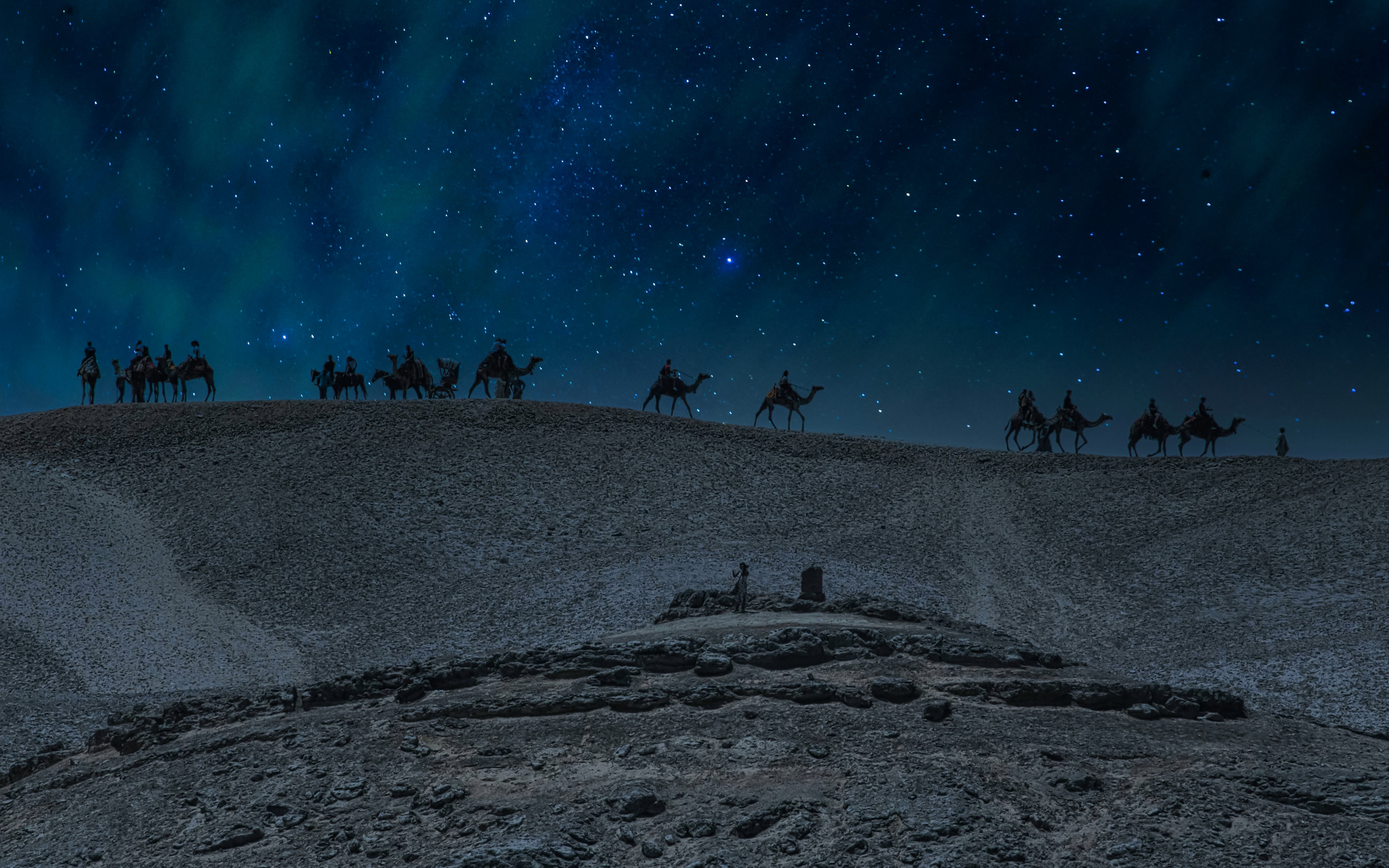 Camel caravan under starry sky in Doha desert safari at night.