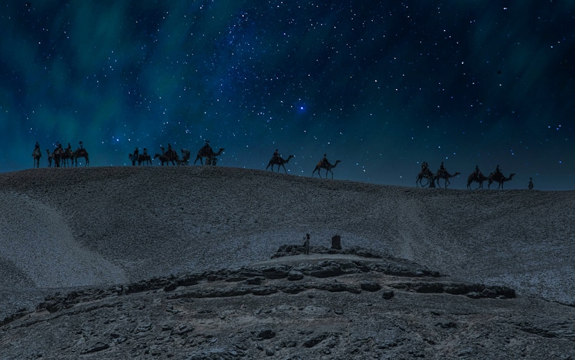 Camel caravan under starry sky in Doha desert safari at night.
