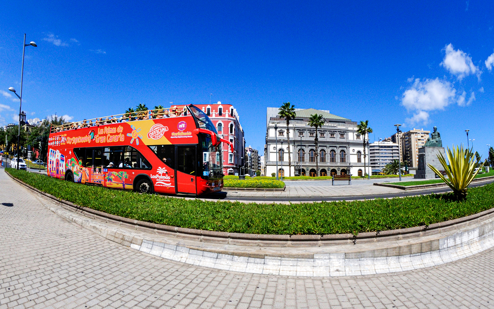 Red double-decker bus on Las Palmas street with historic buildings in the background.