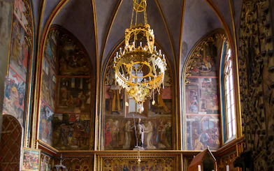 Prague Castle interior with ornate chandelier and detailed wall frescoes.
