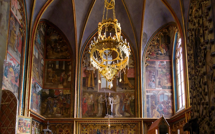 Prague Castle interior with ornate chandelier and detailed wall frescoes.