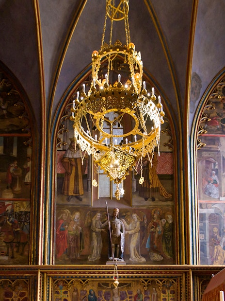 Prague Castle interior with ornate chandelier and detailed wall frescoes.