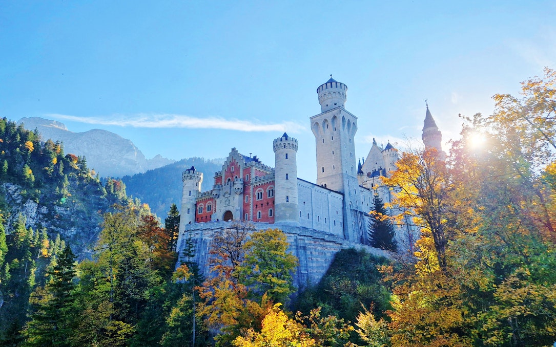 Neuschwanstein Castle in Bavaria surrounded by autumn trees and mountains.
