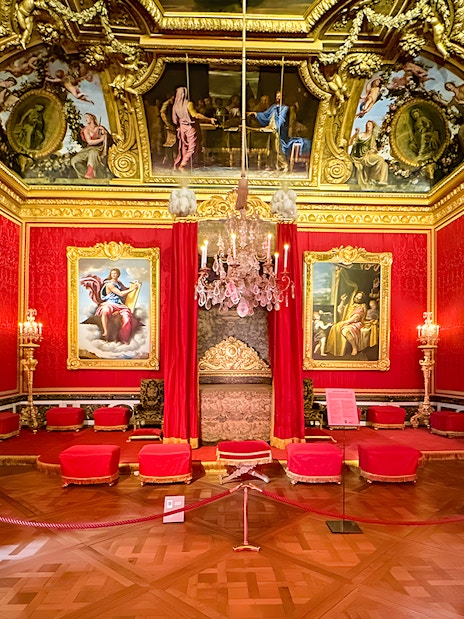 Palace of Versailles Royal Quarters interior with ornate red furnishings and detailed ceiling.