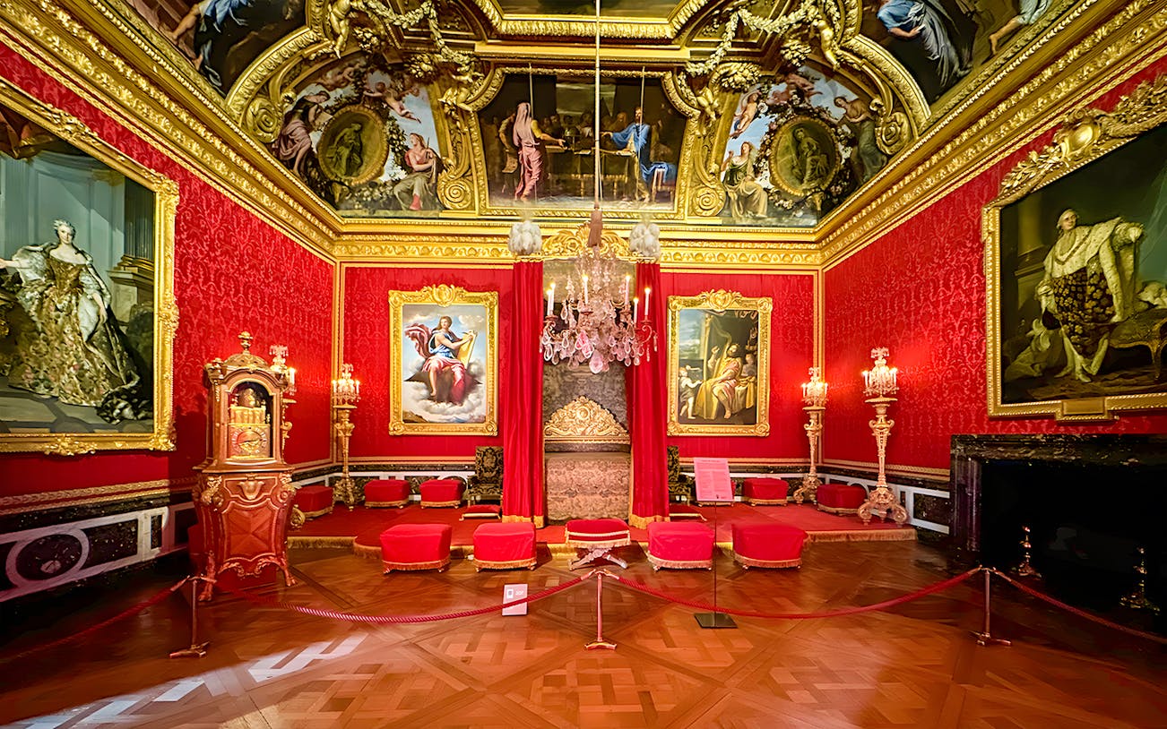 Palace of Versailles Royal Quarters interior with ornate red furnishings and detailed ceiling.