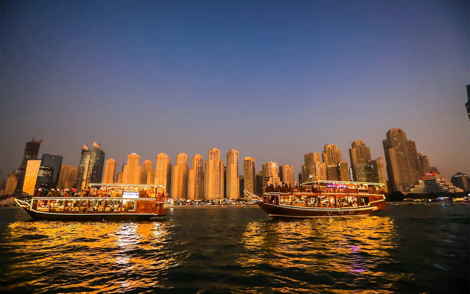 dubai city skyline bathed in golden light during sunset as seen from the dubai cruises experience