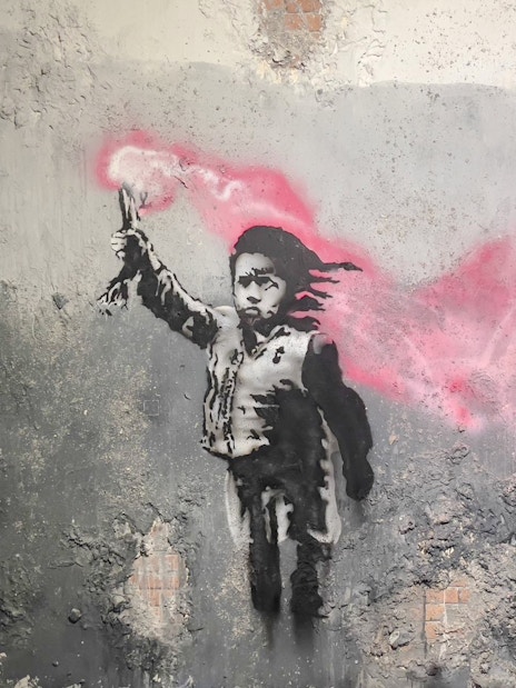 Street art of a child with a pink flare at Banksy Museum, Amsterdam.