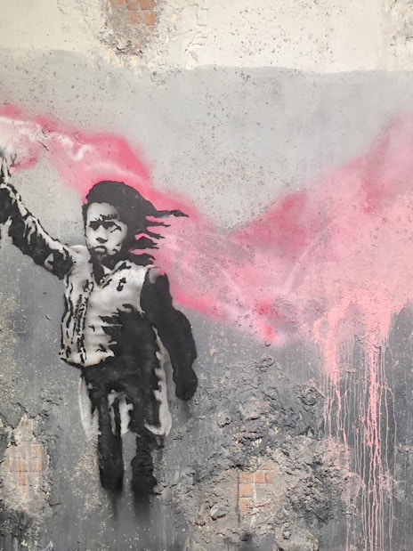 Street art of a child with a pink flare at Banksy Museum, Amsterdam.