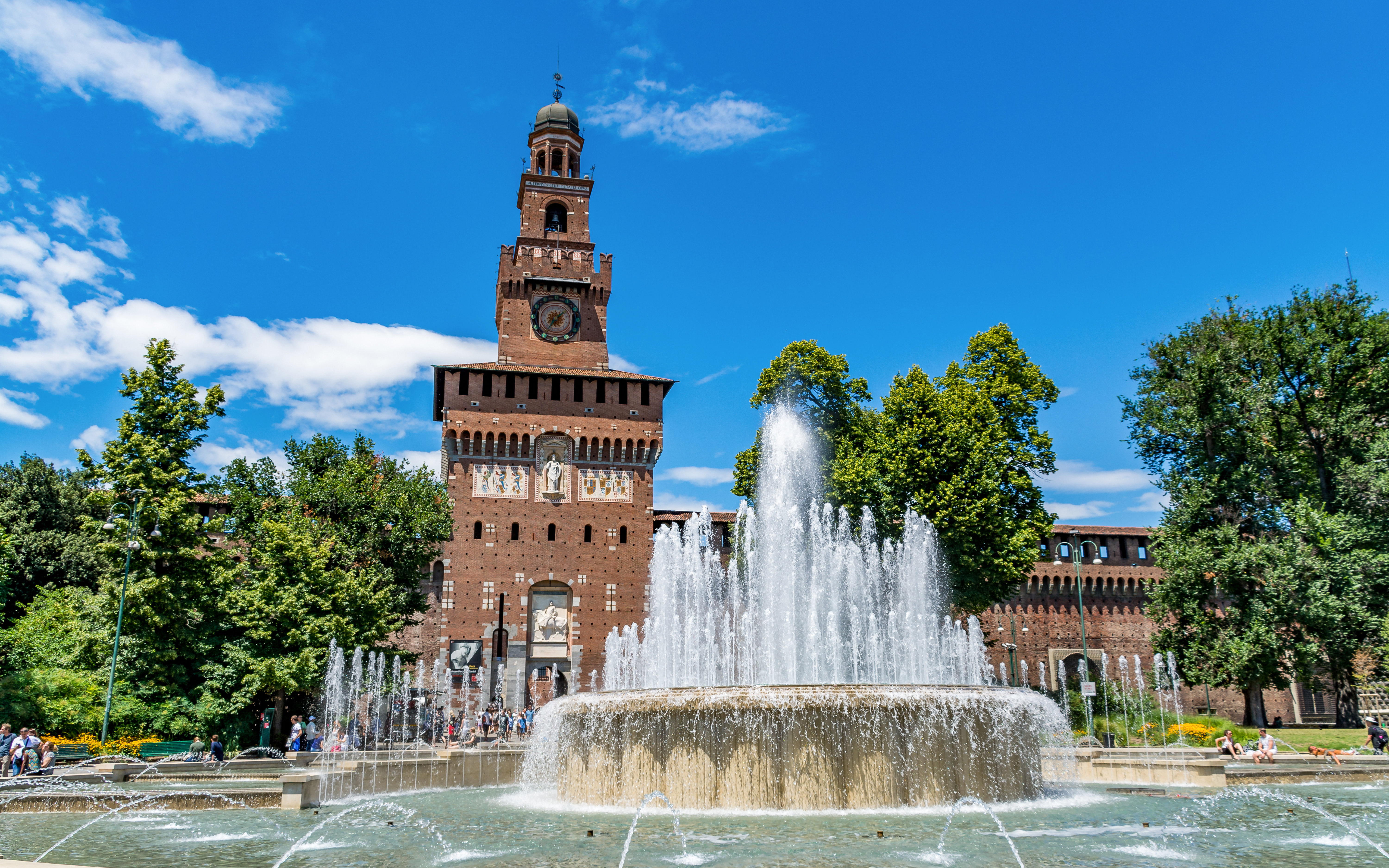 Fountain in front of Sforza Castle, Milan, with clock tower and trees.